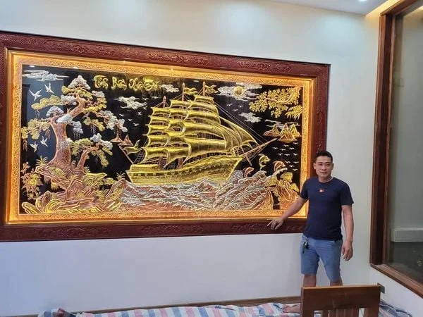 Người đàn ông treo tranh thuận buồm xuôi gió