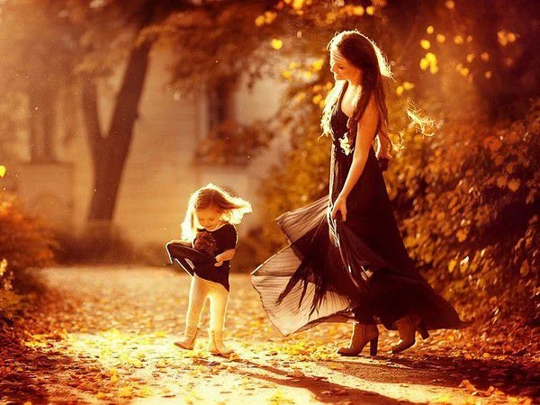 Hình ảnh mẹ và con gái nhỏ dạo bước trên con đường lá vàng mùa thu