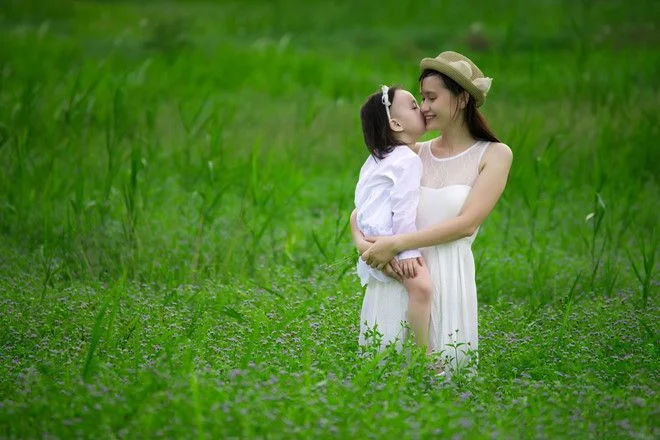 Hình ảnh mẹ và con gái ôm nhau tình cảm giữa cánh đồng cỏ xanh