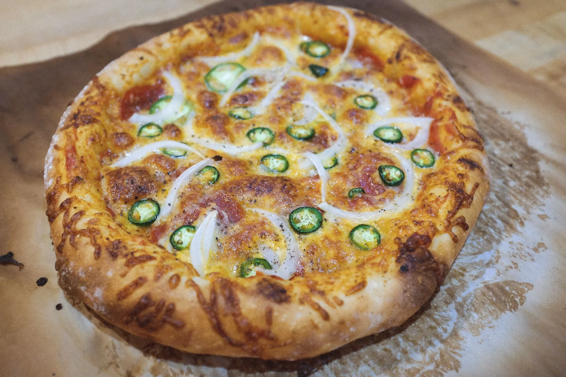 Pizza tròn phủ phô mai, hành tây và ớt xanh