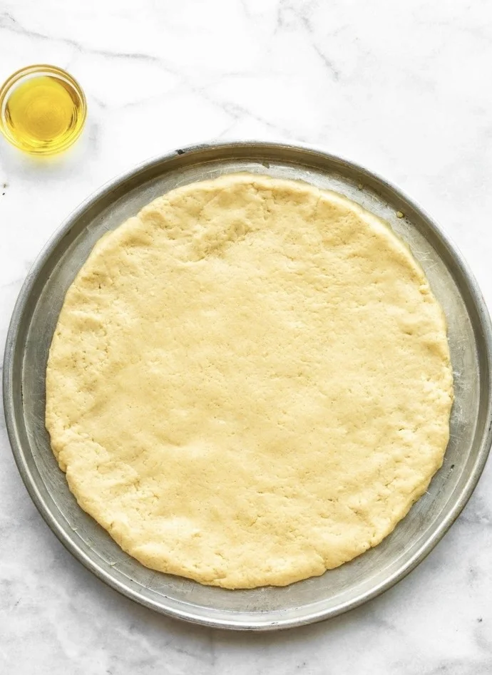 Đế pizza chưa nướng đặt trên khay tròn
