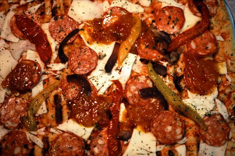 Pizza phủ nhiều loại xúc xích, thịt nguội và rau củ