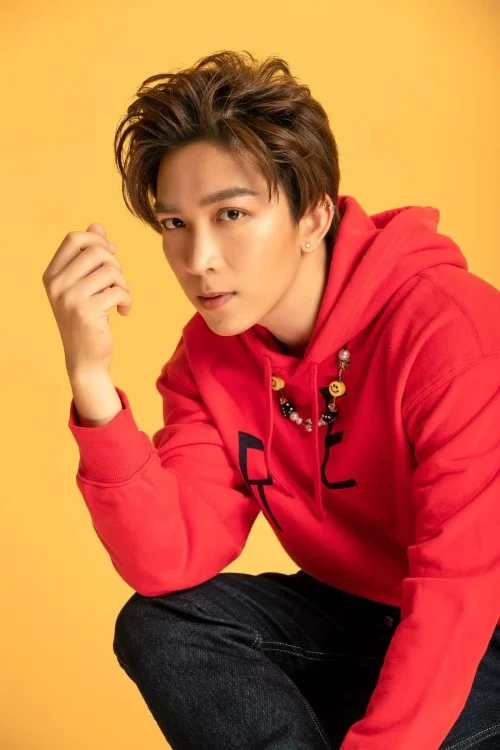 Ảnh chân dung nam trẻ mặc áo hoodie đỏ tạo dáng trước phông nền vàng cam