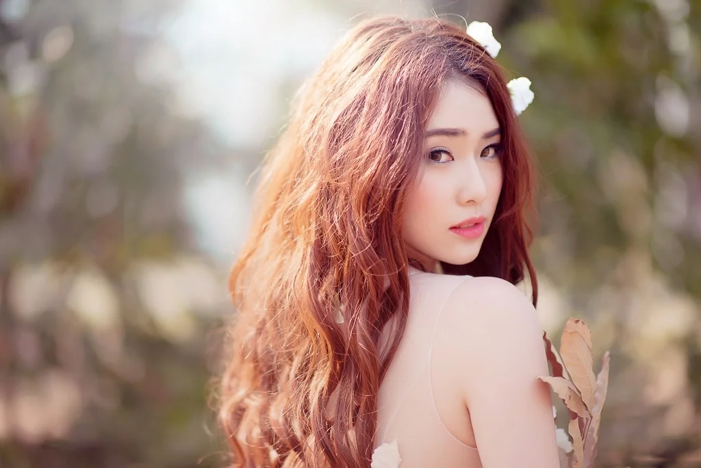 Ảnh chân dung cô gái tóc đỏ xoăn nhìn qua vai ngoài trời