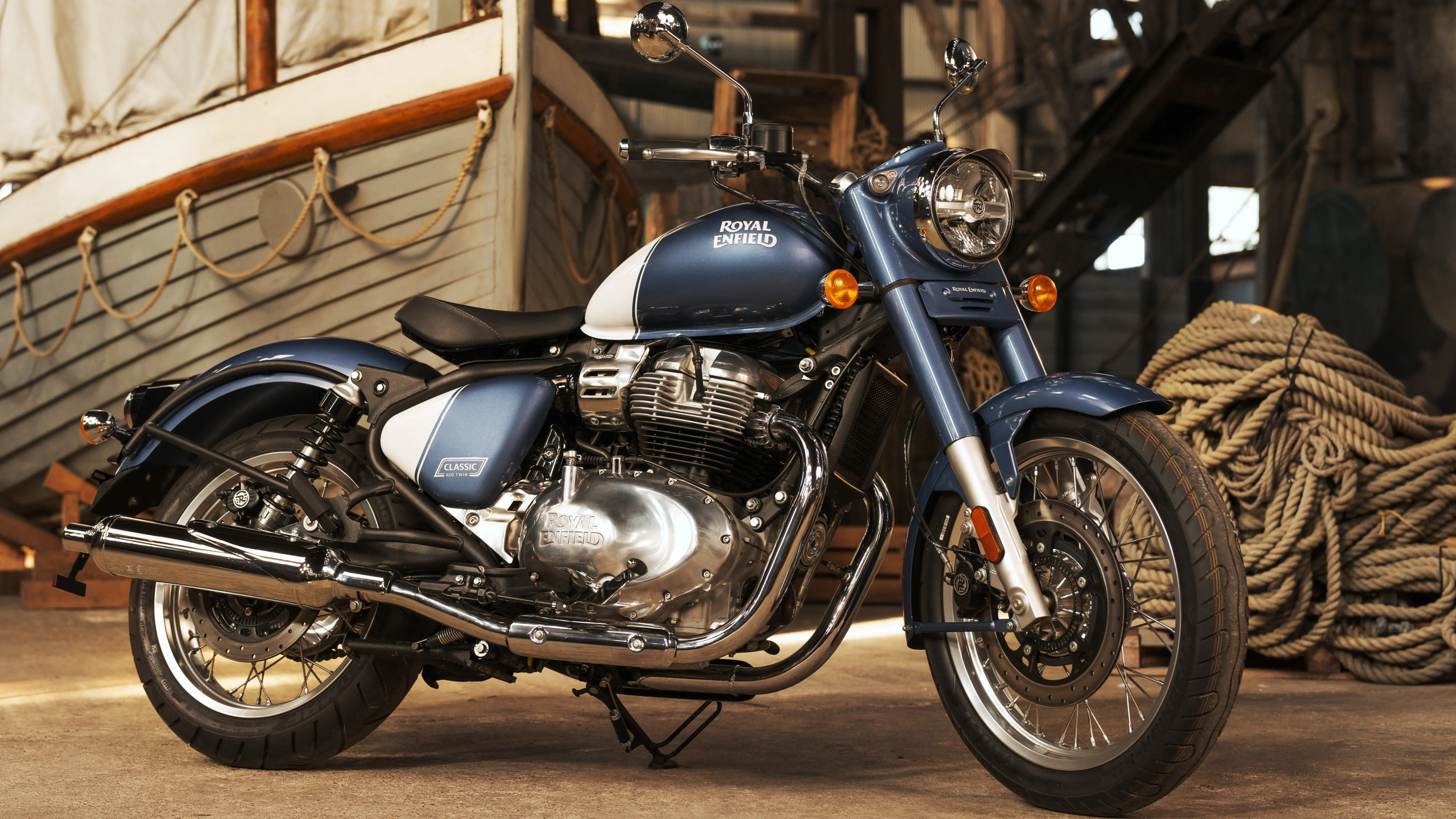 Hình nền đẹp ngầu với xe mô tô Royal Enfield màu xanh cổ điển trong nhà kho ven cảng.