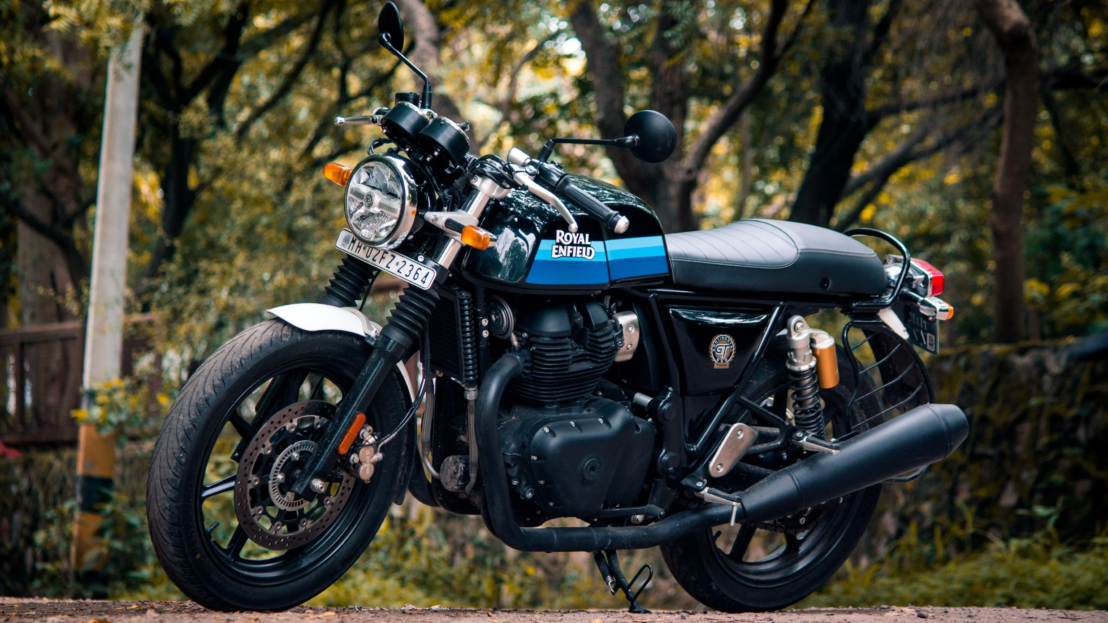 Hình nền đẹp ngầu với xe mô tô Royal Enfield màu đen xanh đỗ giữa khu rừng xanh