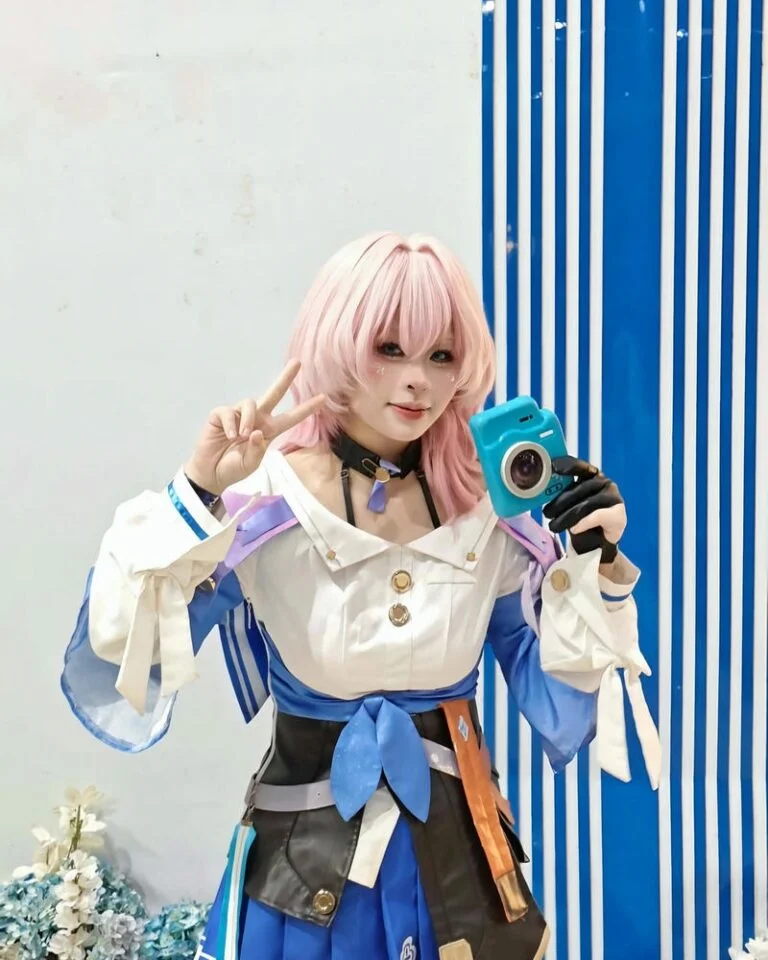 Cosplay anime nữ tóc hồng cầm máy ảnh