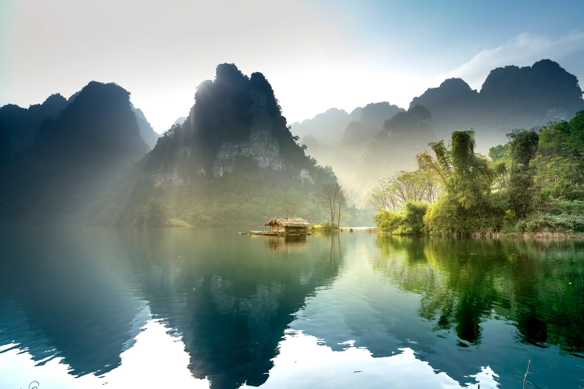 Khung cảnh phong cảnh thiên nhiên tuyệt đẹp với căn nhà gỗ nhỏ trên hồ nước và núi đá vôi hùng vĩ.